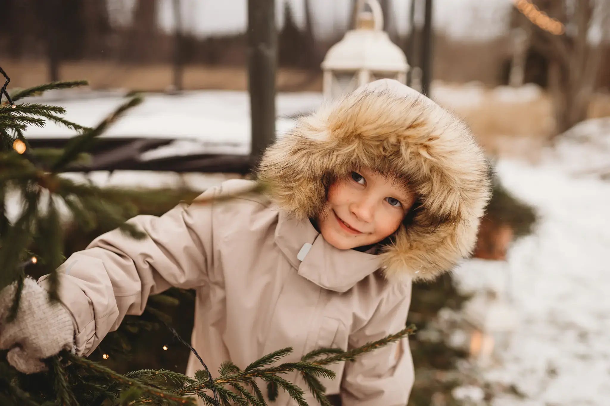 Child in a winter coat smiling with Acon trampoline in the background.