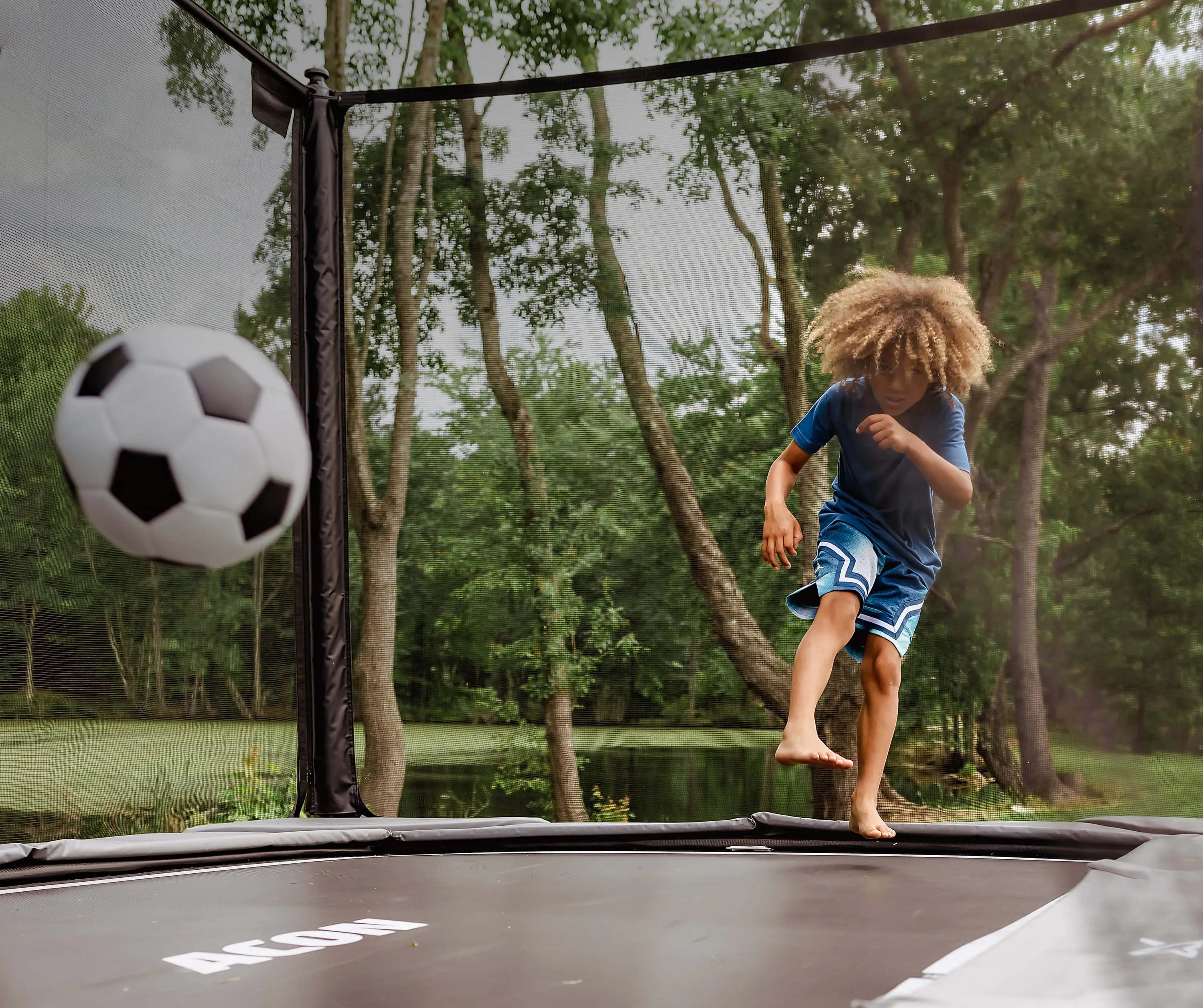 A boy plays football on the Acon X Trampoline.