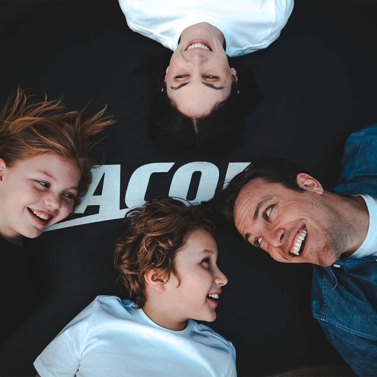 Father, mother and two kids laying on an Acon trampoline.