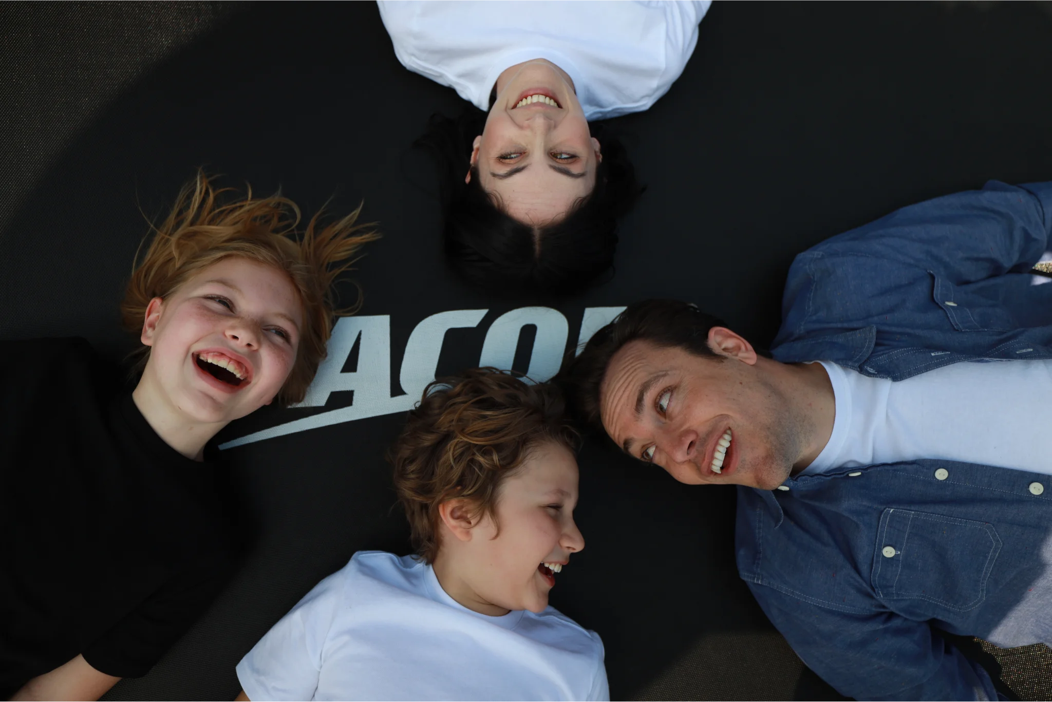 Happy family of four laying on an Acon trampoline.