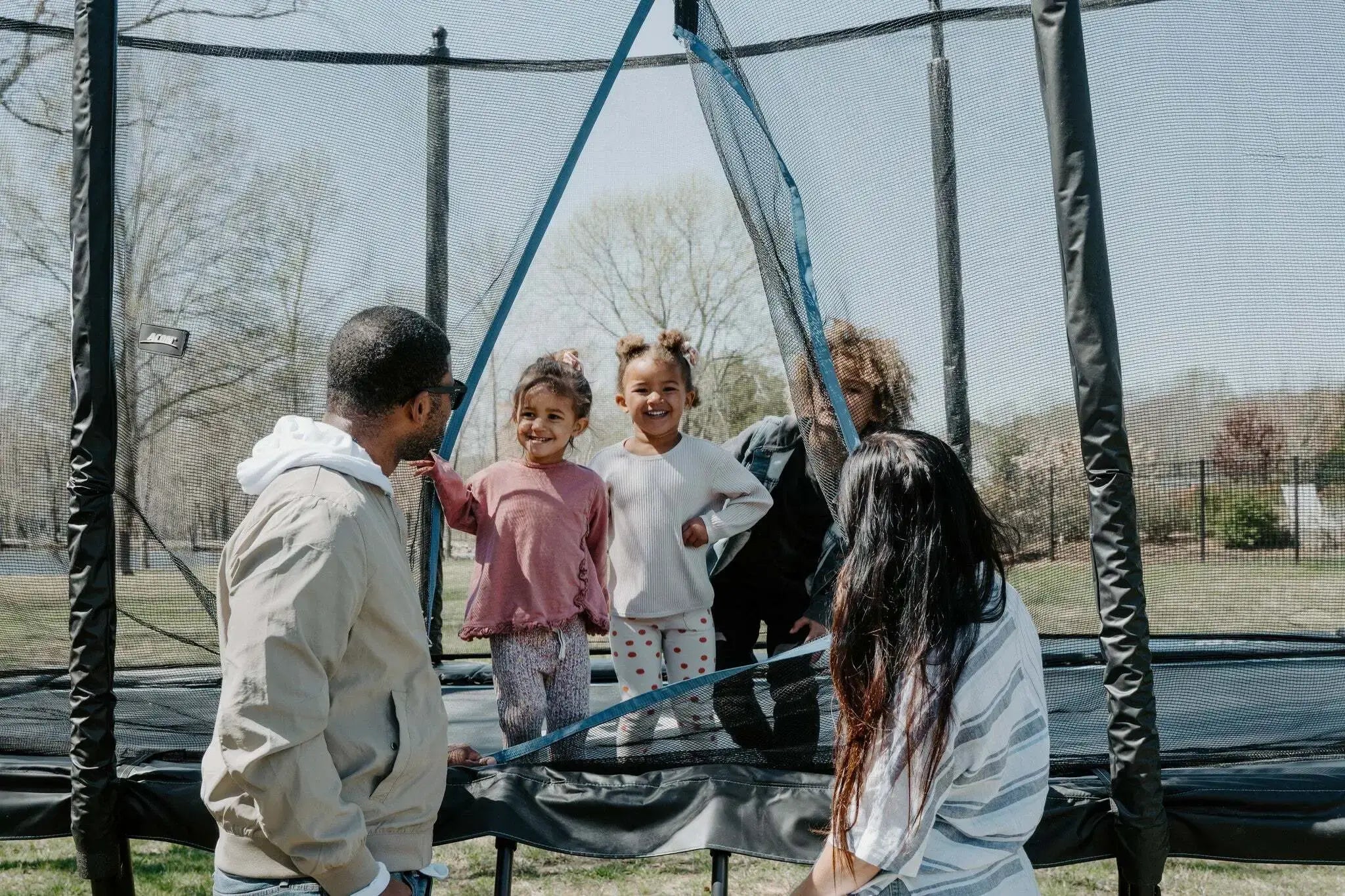 Family with three kids outside with a trampoline.